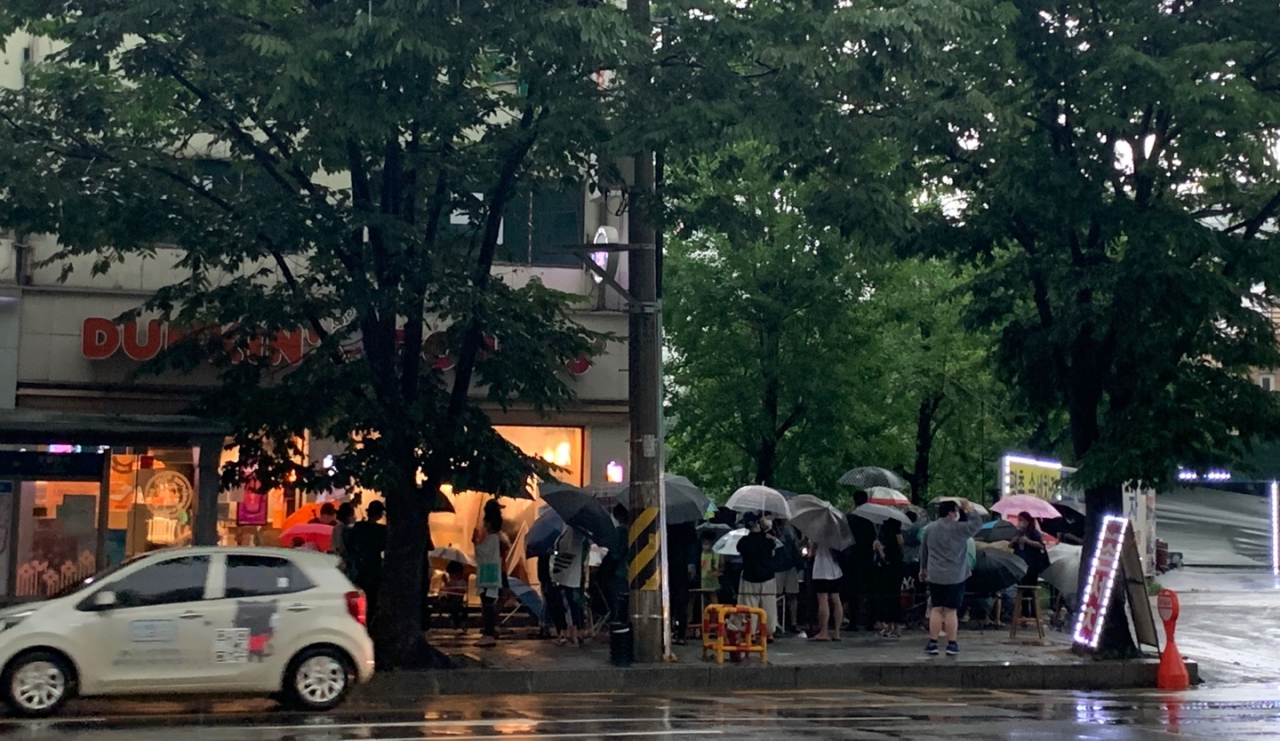 지난 5일 4시께 경기도 안양시 던킨도너츠 평촌점에서 캠핑용품 굿즈 폴딩박스를 구매하기 위해 빗속에서 사람들이 줄 서 있다. [사진=김빛나 기자]