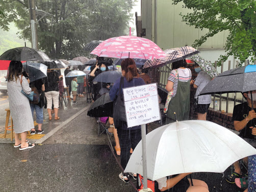 지난 5일 오후 4시께 경기도 안양시 던킨도너츠 평촌점에서 캠핑용품 굿즈 폴딩박스를 구매하기 위해 빗속에 사람들이 줄 서 있다. [김빛나 기자]