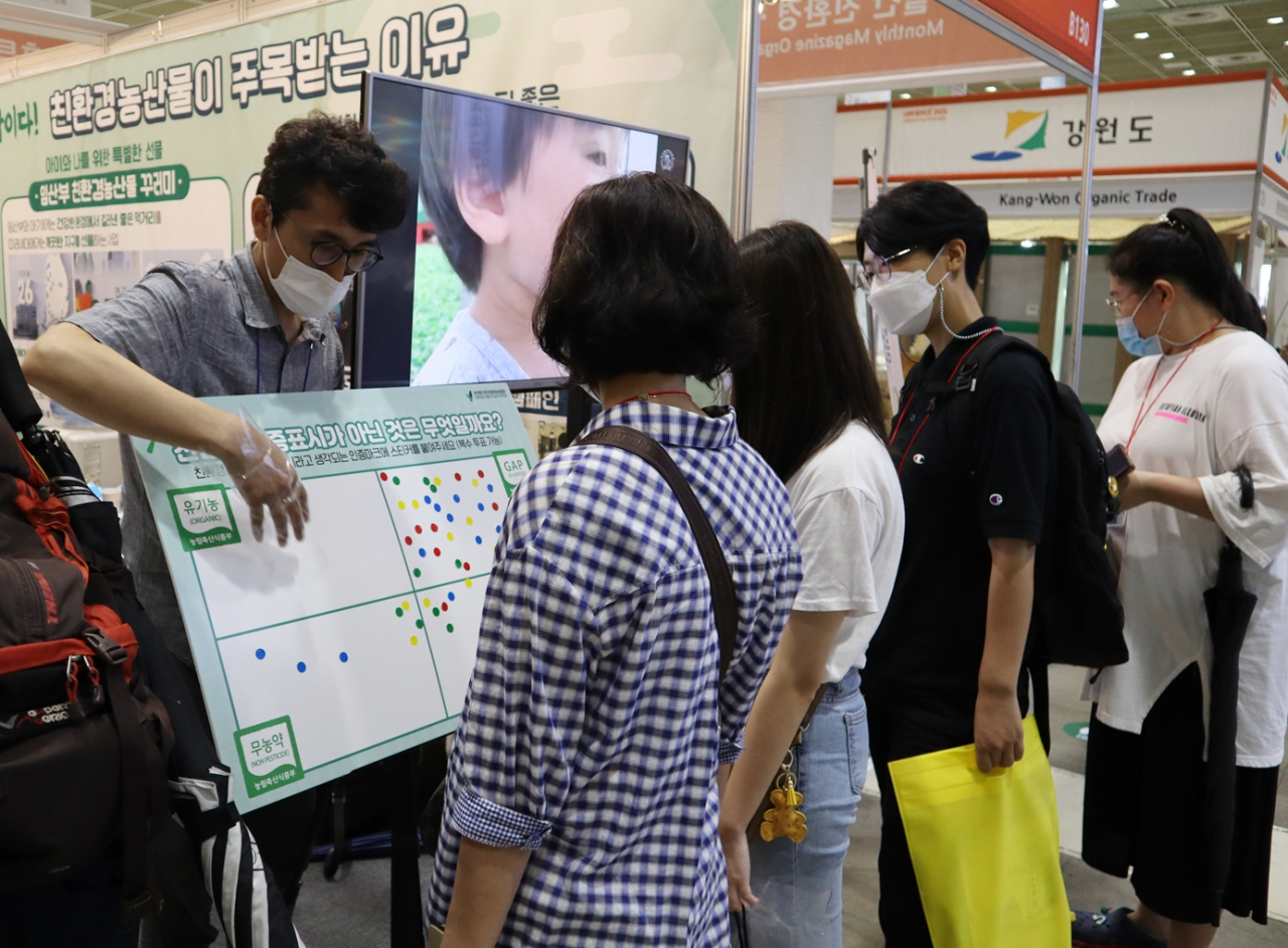참관객들이 친환경농산물자조금위원회 홍보 부스에서 친환경농산물 인증 마크에 대한 설명을 듣고 있다.[사진=친환경농산물자조금위원회]