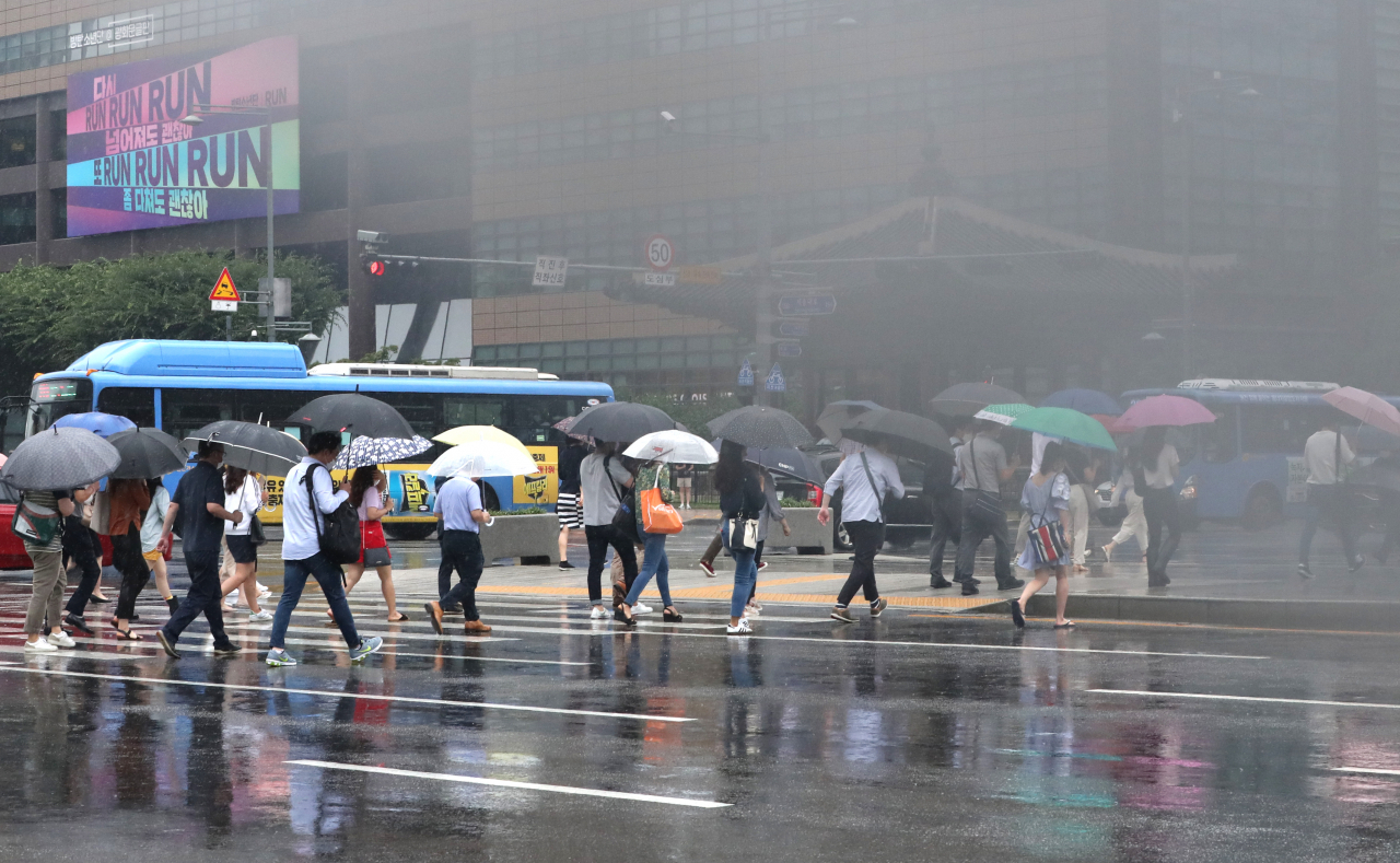 강풍이 불고 비가 내린 지난 6일 오전 출근길에 나선 시민들이 우산을 쓰고서 서울 광화문 네거리를 지나고 았다. [연합]