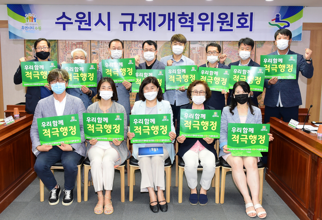 조청식 제1부시장(뒷줄 왼쪽 4번째)을 비롯한 수원시 규제개혁위원회 위원들이 ‘우리함께 적극행정’이라는 문구가 적힌 손팻말을 들고, 기념촬영을 하고 있다. [수원시 제공]