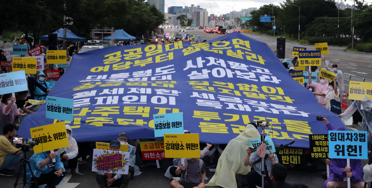 정부의 부동산 규제 정책에 반대하는 시민들이 8일 서울 여의도에서 열린 집회에서 임대차3법 등에 반대하는 구호를 외치며 대형 현수막을 펼치고 있다. 연합뉴스