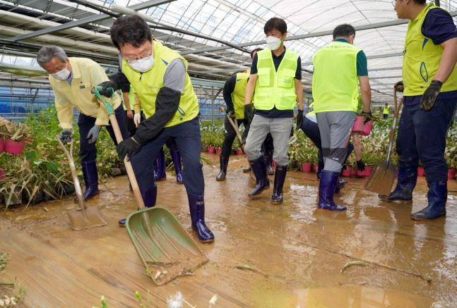 NH NongHyup Chairman Kim Gwang-soo (second from left) volunteers with employees on repairing damaged facilities at a plant farm in Yongin, Gyeonggi Province. (NH NongHyup)　