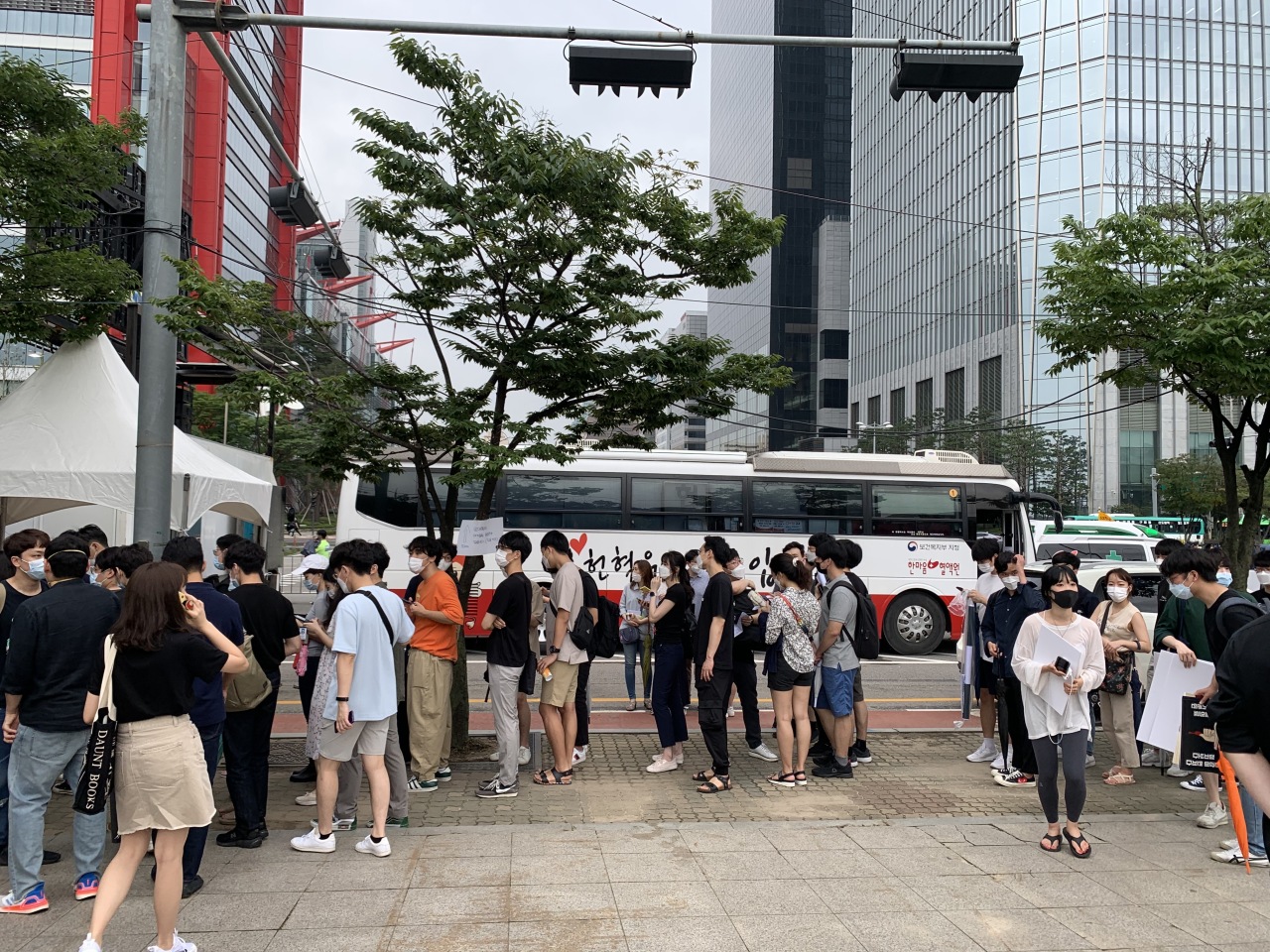 Junior doctors line up to get their symptoms checked before they participate in the march. Behind them is a blood donation vehicle where the young doctors donated blood. (Kim Arin/The Korea Herald)