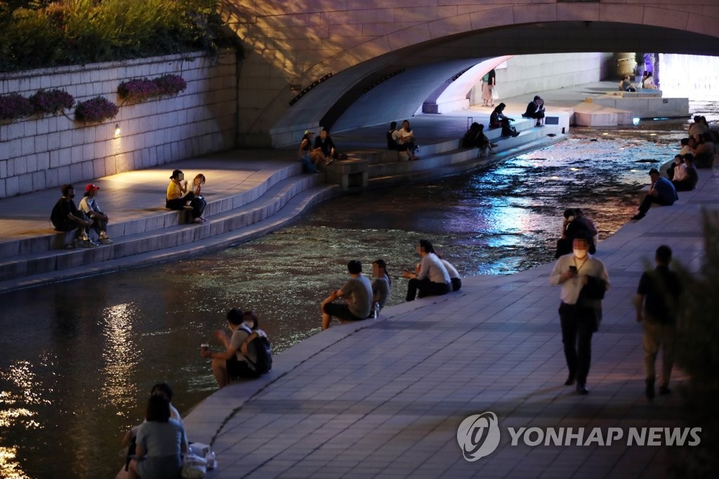 Citizens sit along Cheonggye Stream in central Seoul on the night of June 22, as hot weather continued after the daytime temperature reached the year’s high of 35.4 degree Celsius. (Yonhap)