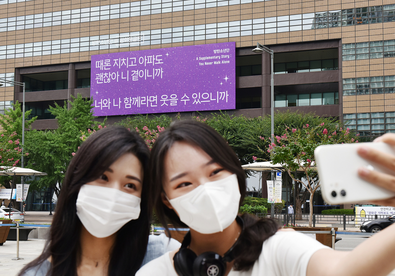 18일 시민들이 교보생명 방탄소년단 가사로 꾸며진 '광화문글판 두 번째 특별편'이 내걸린 광화문 교보생명빌딩을 배경으로 사진을 찍고 있다.