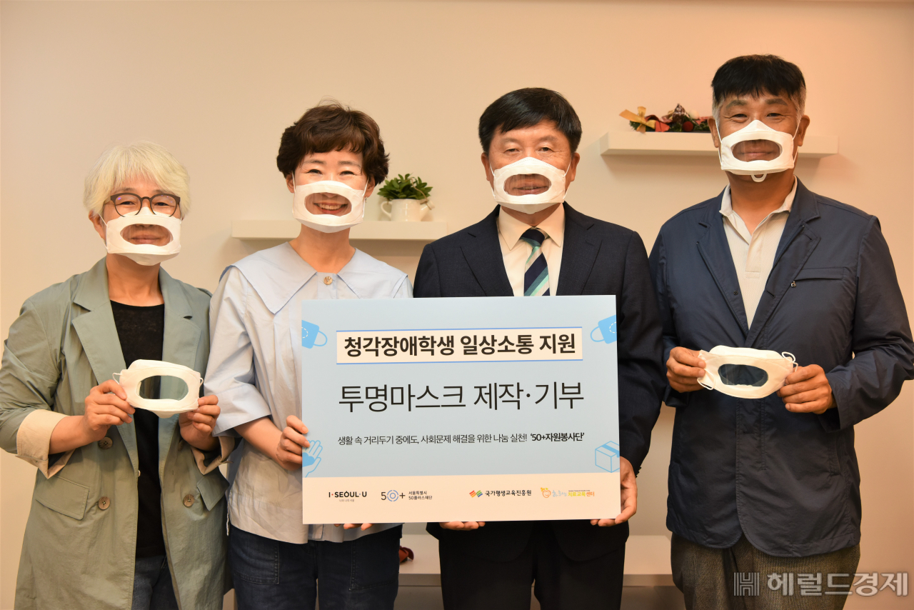 50세 이상 자원봉사자들이 투명마스크를 쓰고 기념촬영을 하고 있다. [서울시 제공]