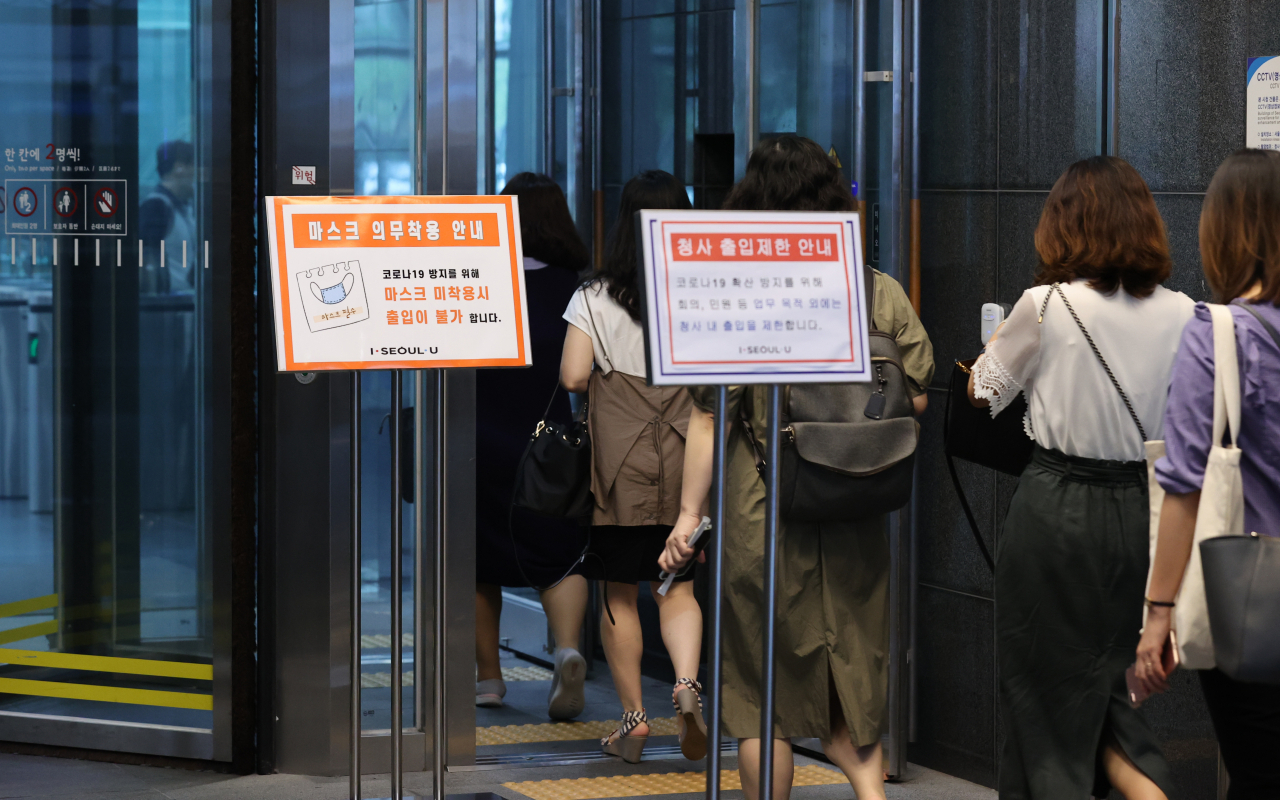 20일 오전 서울 중구 태평로 시청 신청사 건물로 직원들이 출근하고 있다. 전날 시청 직원 중 신종 코로나 바이러스 감염증(코로나19) 확진자가 발생하면서 시청 신청사 건물은 폐쇄됐고 방역 조치를 마친 뒤 이날 확진자가 발생한 2층을 제외하고 다시 문을 열었다. [연합]