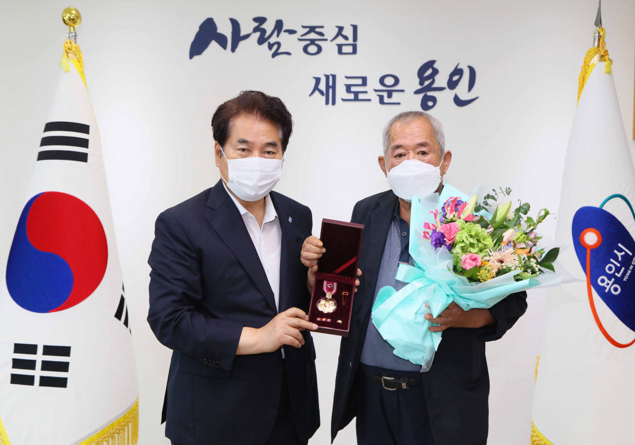 백군기 시장이 6.25전쟁 참전유공자 유족에 훈장을 전수하고 기념촬영을 하고 있다. [용인시 제공]