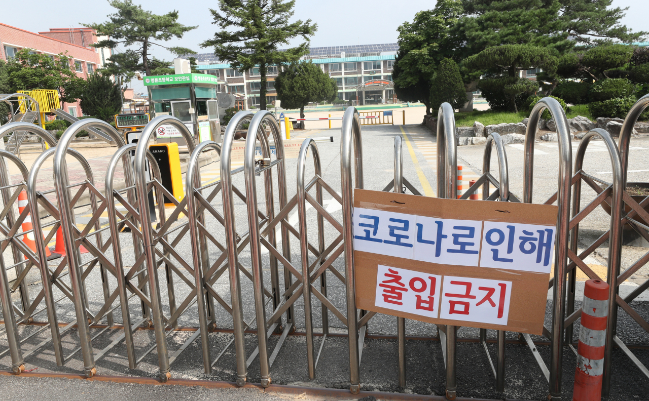 21일 강원 원주시 개운동 명륜초등학교의 굳게 닫힌 교문 위로 ‘코로나로 인해 출입금지’ 팻말이 붙어 있다. 이 학교는 병설유치원 교사가 이날 새벽 코로나19 확진 판정을 받아 2주 동안 온라인수업을 진행한다. [연합]
