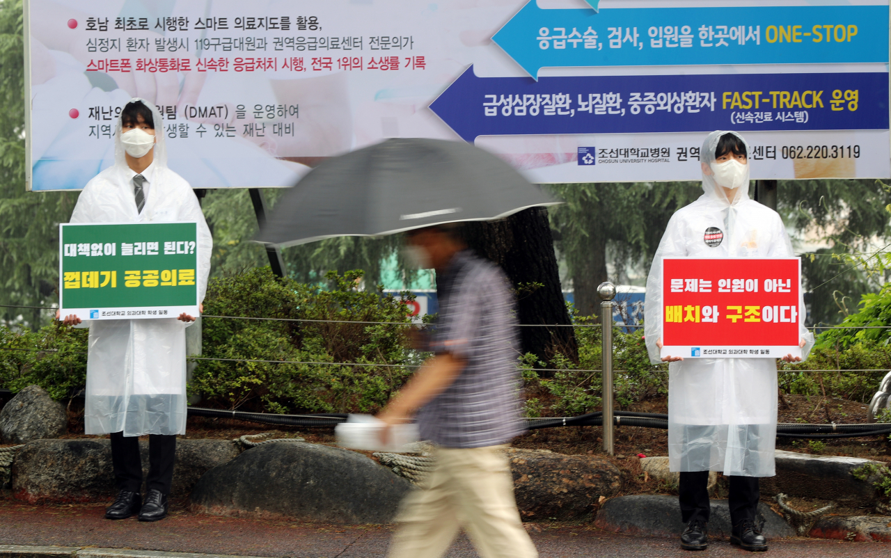 의대 정원 확대 정부 정책에 반발해 전공의들이 파업에 나선 7일 오전 광주 조선대학교병원 앞에서 의대생들이 전공의 파업에 동조하기 위해 구호가 적힌 피켓을 들고 서 있다. [연합뉴스]