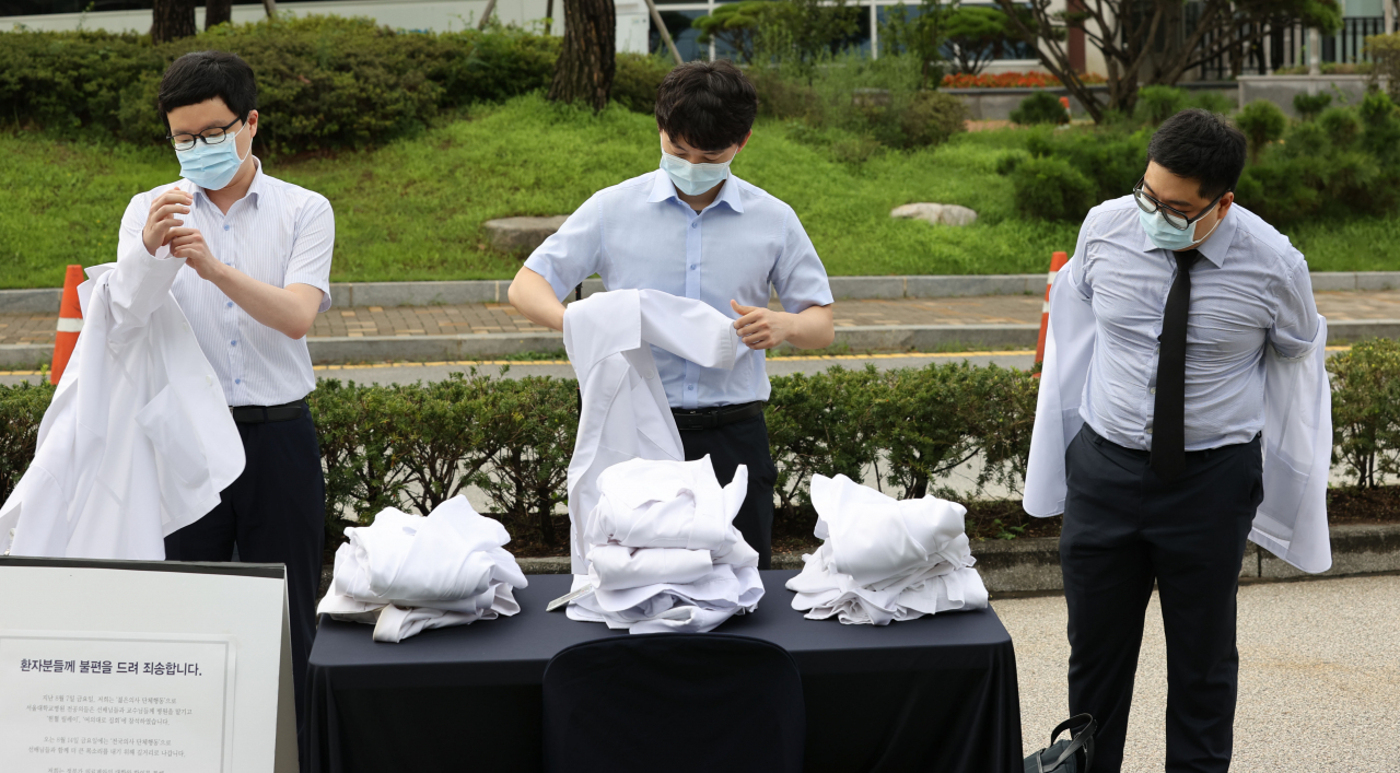 23일 오전 서울 종로구 서울대병원 대학의원 본관 앞에서 정부의 의료정책에 반대하는 전공의들이 의사 가운을 탈의하고 있다. 연합뉴스