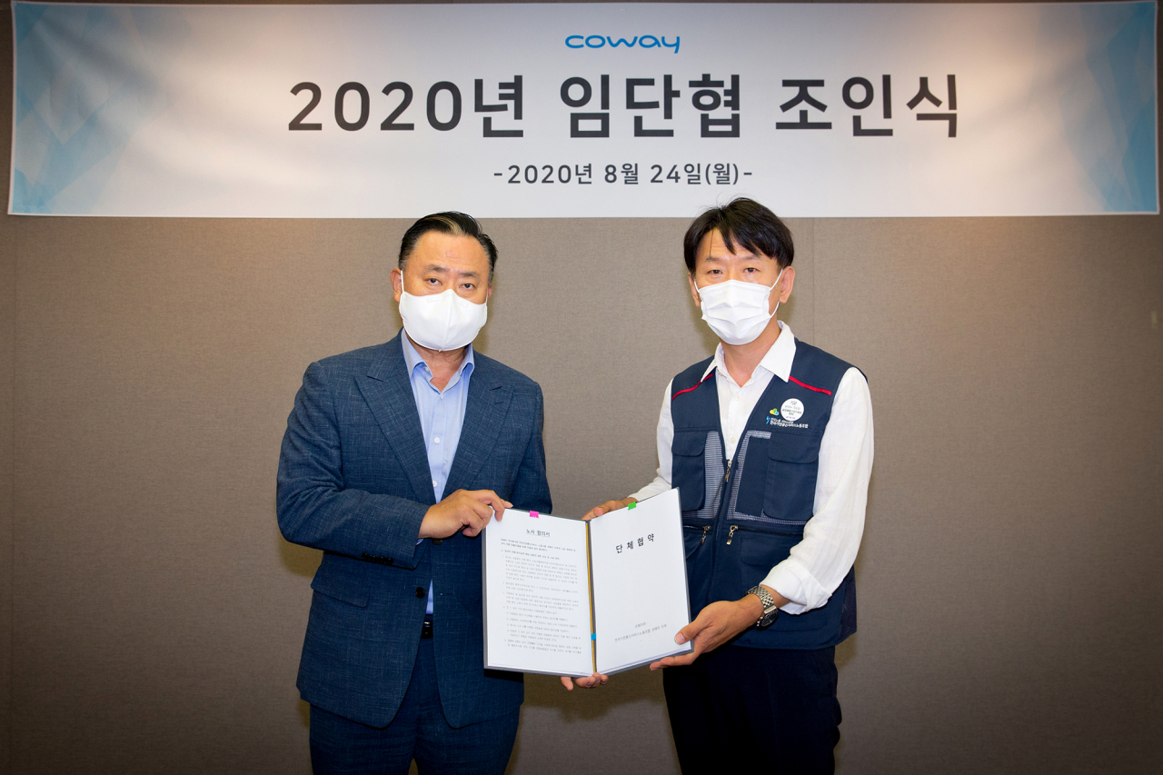 이해선 코웨이 대표이사와 이현철 전국가전통신서비스 노동조합 위원장이 지난 24일 서울 중구의 코웨이 본사에서 CS닥터 정규직 전환에 따른 임금안 등 임금 및 단체협약 합의안에 조인했다.[코웨이 제공]