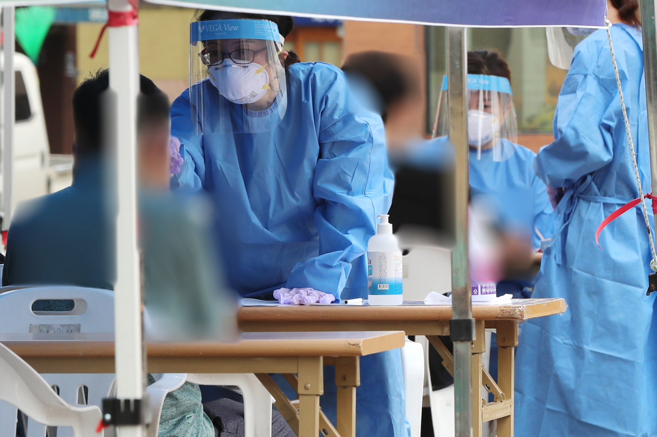 서울 성북구 코로나19 선별진료소에서 시민들이 검체 채취를 받기 전 문진표를 작성하고 있다. [연합뉴스]