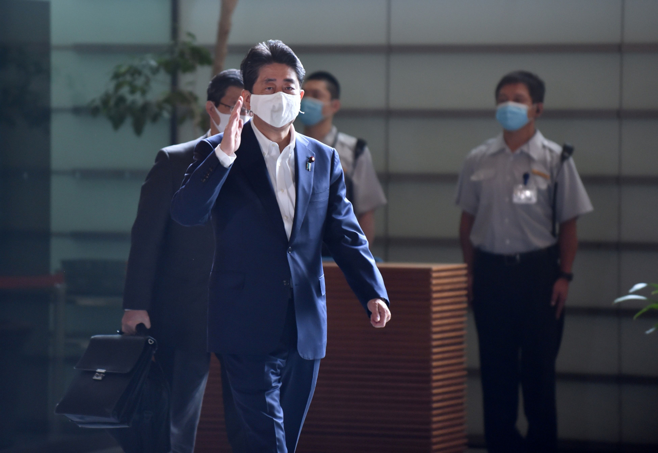건강 이상설이 나돌고 있는 아베 신조 일본 총리가 27일 마스크를 쓰고 도쿄의 총리 관저로 출근하며 인사를 하고 있다. 아베 총리는 28일 기자회견을 통해 건강 문제를 언급할 것으로 예상되고 있다. [연합]