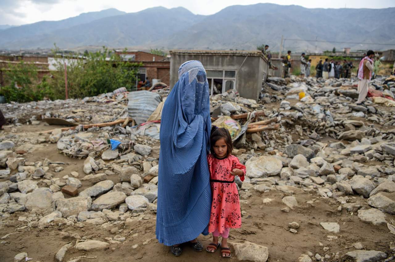 A burqa-clad woman stands near a young girl among households' debris after a flash flood affected the area at Sayrah-e-Hopiyan in Charikar, Parwan province, on Aug. 26, 2020. (AFP)