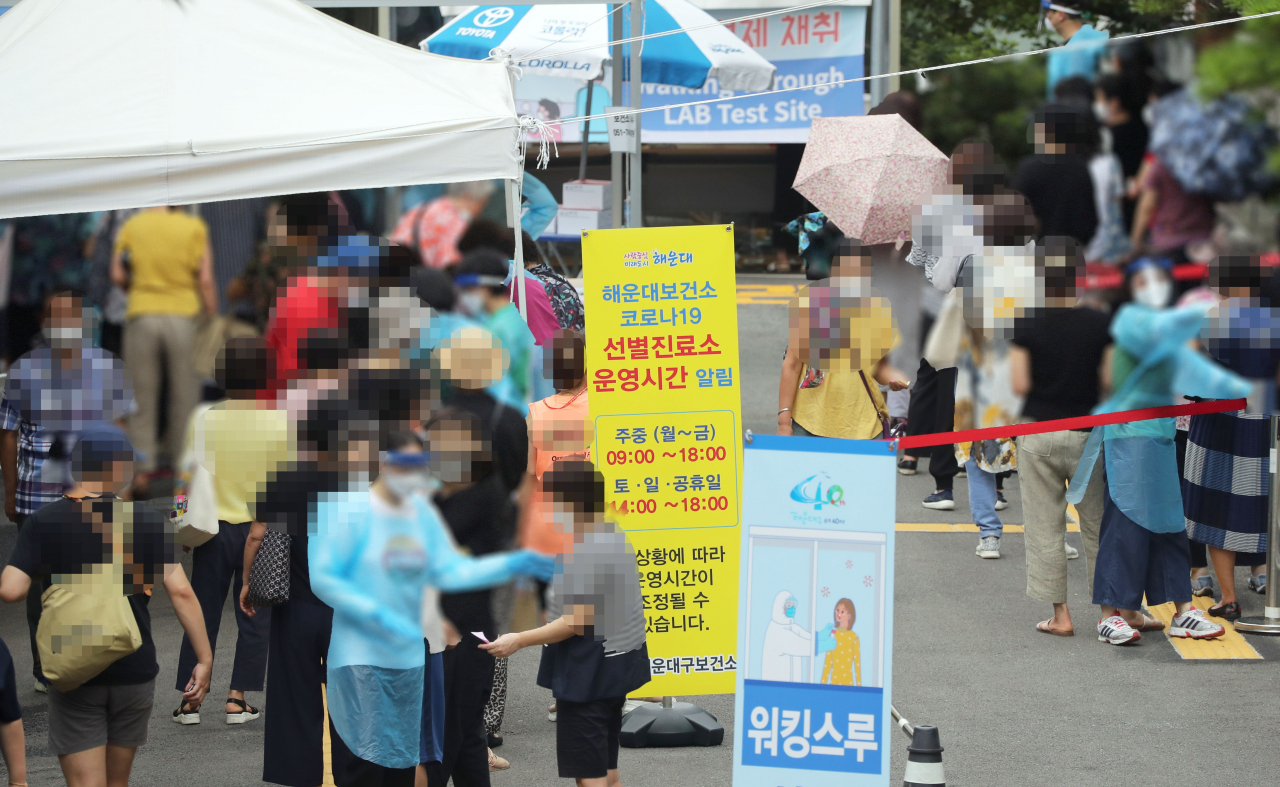 지난달 28일 부산 해운대구보건소 야외에 마련된 선별진료소에서 시민들이 코로나19 진단 검사를 받기 위해 길게 줄을 서 대기하고 있다. 해운대에 있는 한 대형목욕탕 종업원이 확진 판정을 받아 방역 당국과 목욕탕 이용자들이 긴장하고 있다. [연합]