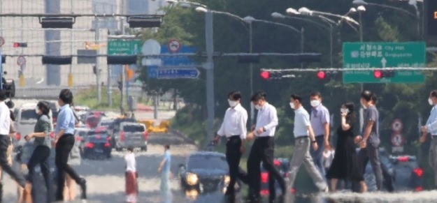전국적인 더위가 계속된 지난 25일 지열로 달아오른 서울 영등포구 여의대로 위로 마스크를 쓴 시민들이 지나고 있다. [연합]