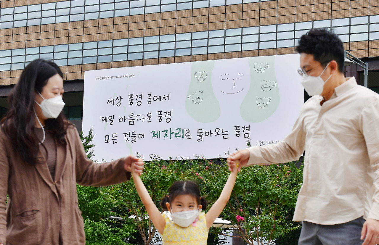 31일 한 가족이 교보생명 '광화문글판 30년 기념편'이 내걸린 광화문 교보생명빌딩 앞을 걷고 있다.