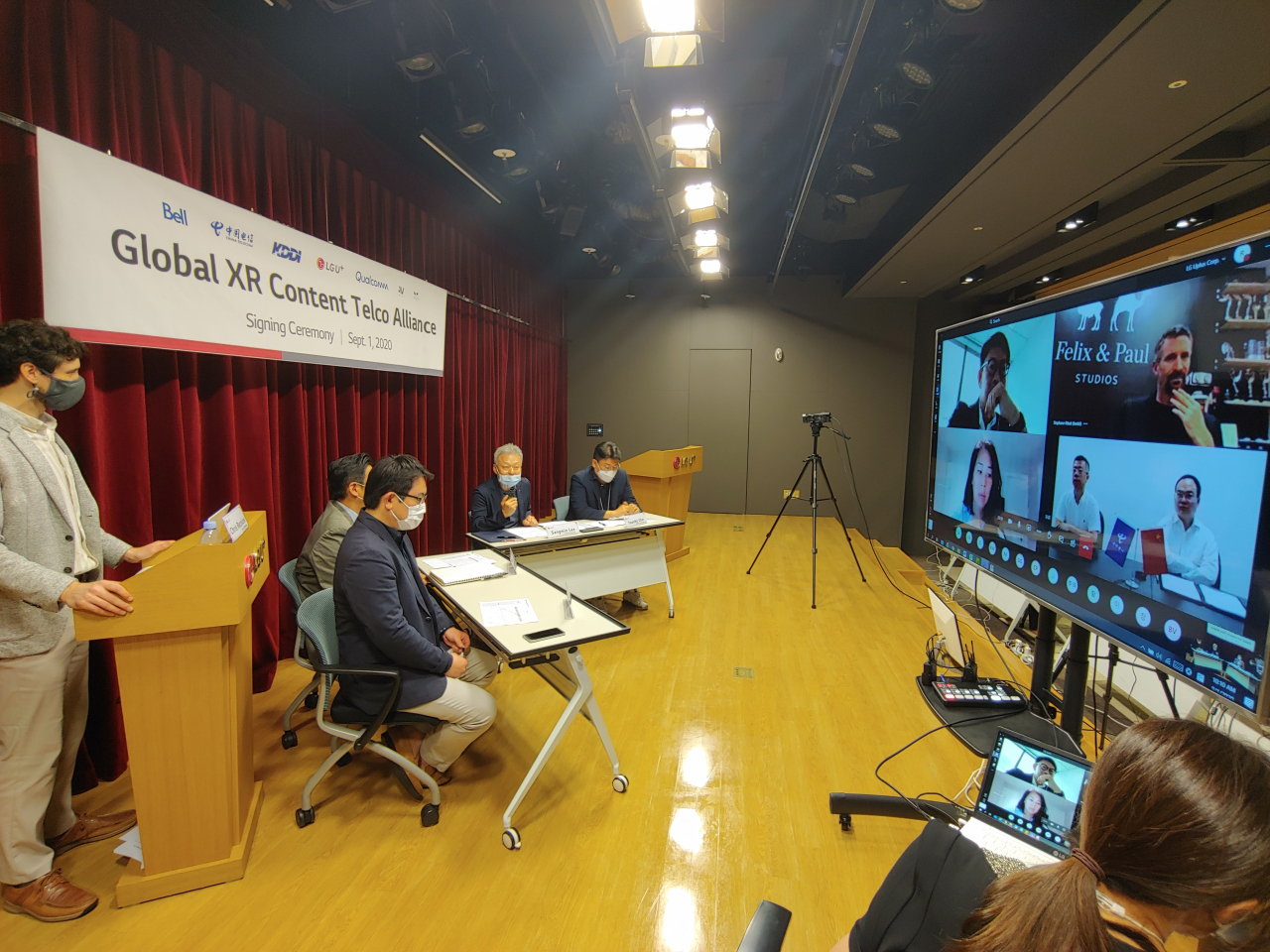 이상민 LG유플러스 부사장(착석자 4명 중 우측에서 2번째)이 화상회의를 통해 XR 얼라이언스 회원사들에게 인사말을 전하는 모습. TV화면 좌측 위부터 시계방향으로 KDDI, 펠릭스 앤 폴 스튜디오, 차이나텔레콤, 벨 캐나다 관계자. [LG유플러스 제공]