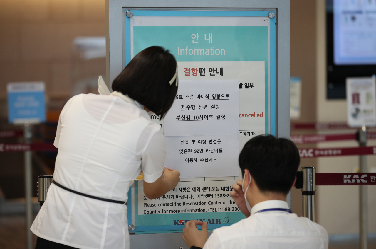제9호 태풍 '마이삭'이 한반도를 향해 북상하고 있는 2일 오전 서울 김포공항 국내선청사에서 관계자들이 항공편 결항 관련 안내문을 붙이고 있다. [연합]