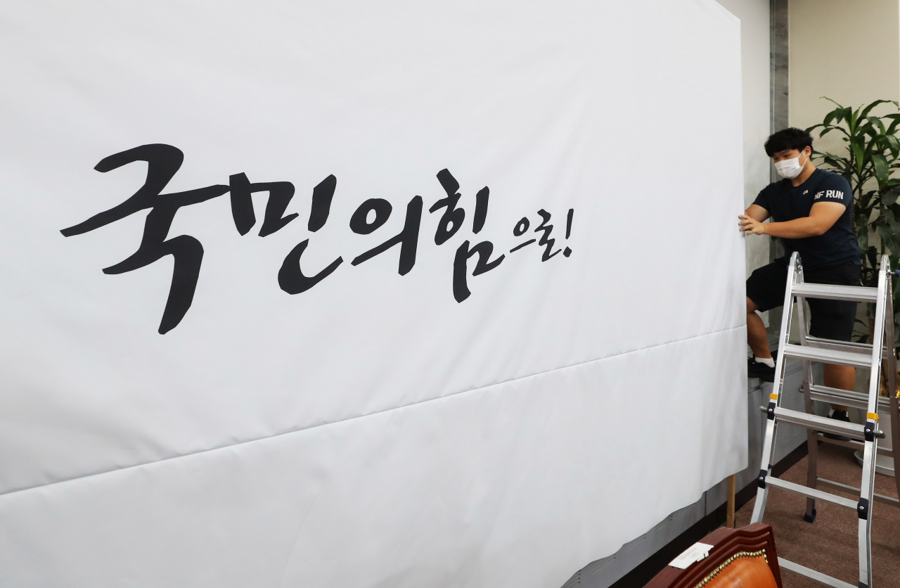 3일 오전 국민의힘 관계자가 국회 당 대회의실 백드롭을 교체하고 있다. [연합]