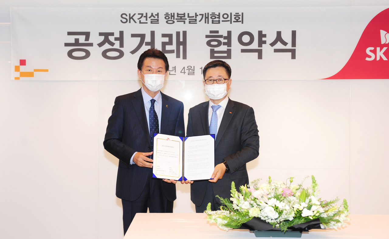 임영문 SK건설 사장(오른쪽), 이재림 행복날개협의회 회장이 공정거래 표준 협약서를 들고 기념촬영을 하고 있다.[SK건설 제공]