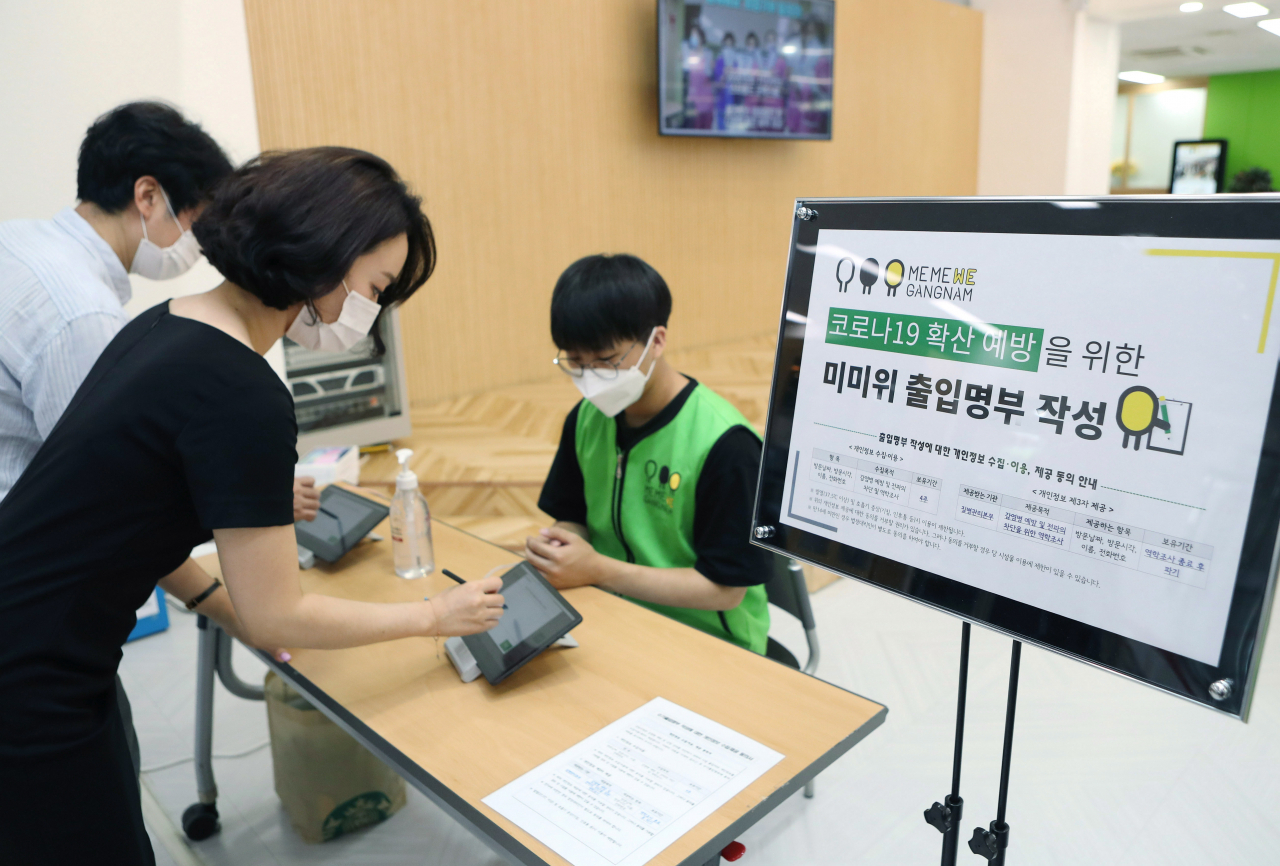강남구청사 앞에서 청사 방문자들이 스마트 출입명부를 쓰고 있다. [강남구 제공]