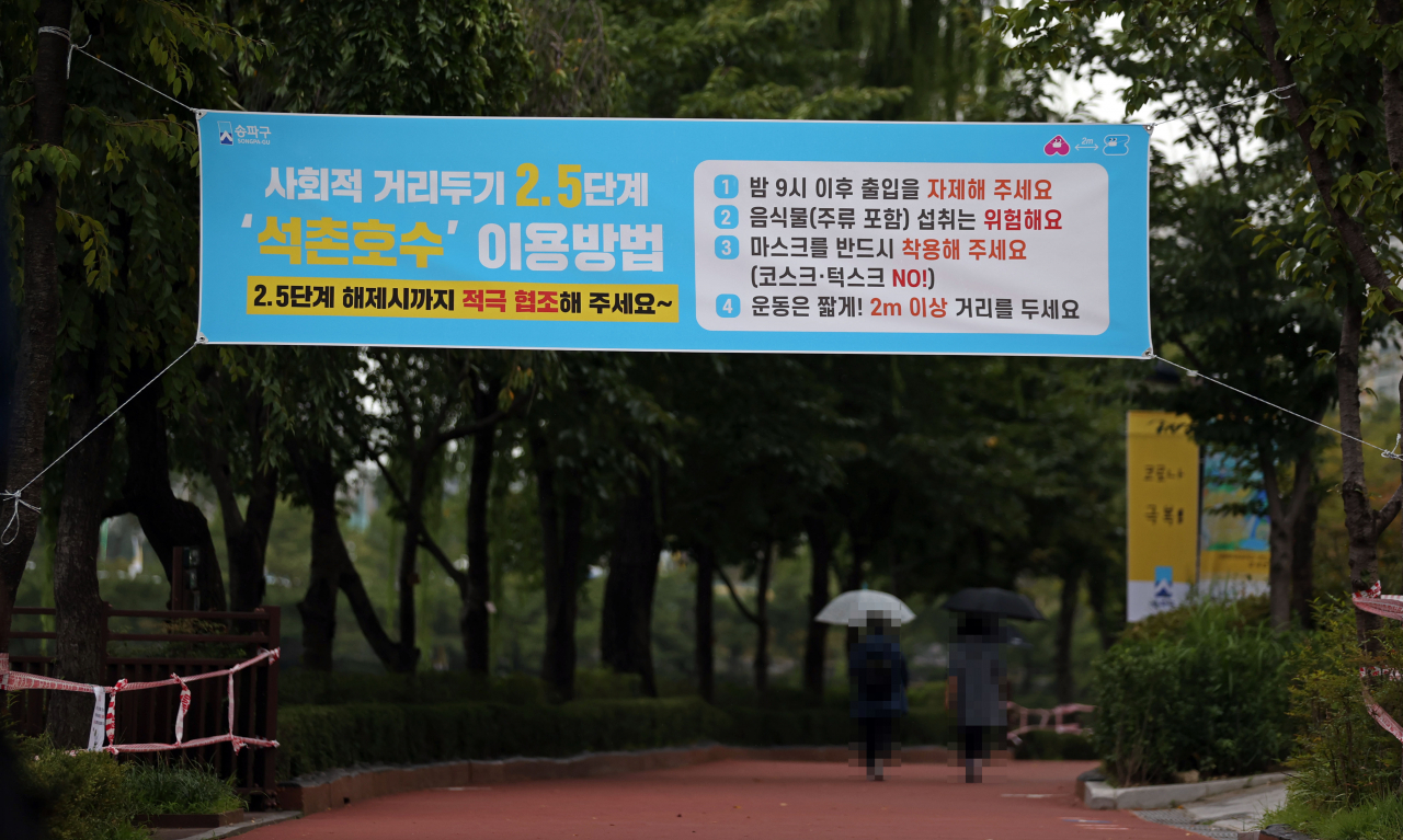 지난 11일 오후 서울 송파구 석촌호수에 신종 코로나바이러스 감염증(코로나19) 확산을 막기 위한 사회적 거리두기 협조 안내 현수막이 걸려있다. 송파구는 11일 오후 6시부터 주말인 13일 밤 12시까지 3일간 석촌호수 내 주요 시설을 임시 폐쇄한다고 밝혔다. [연합]
