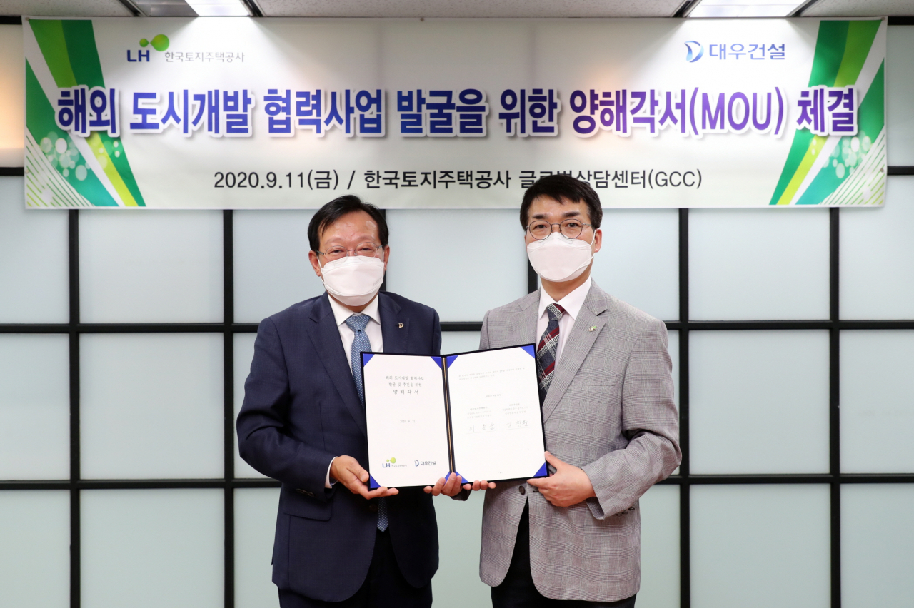 김창환(왼쪽) 대우건설 신사업본부장과 이용삼 한국토지주택공사(LH) 글로벌사업본부장이 양해각서를 체결한 모습. [대우건설 제공]