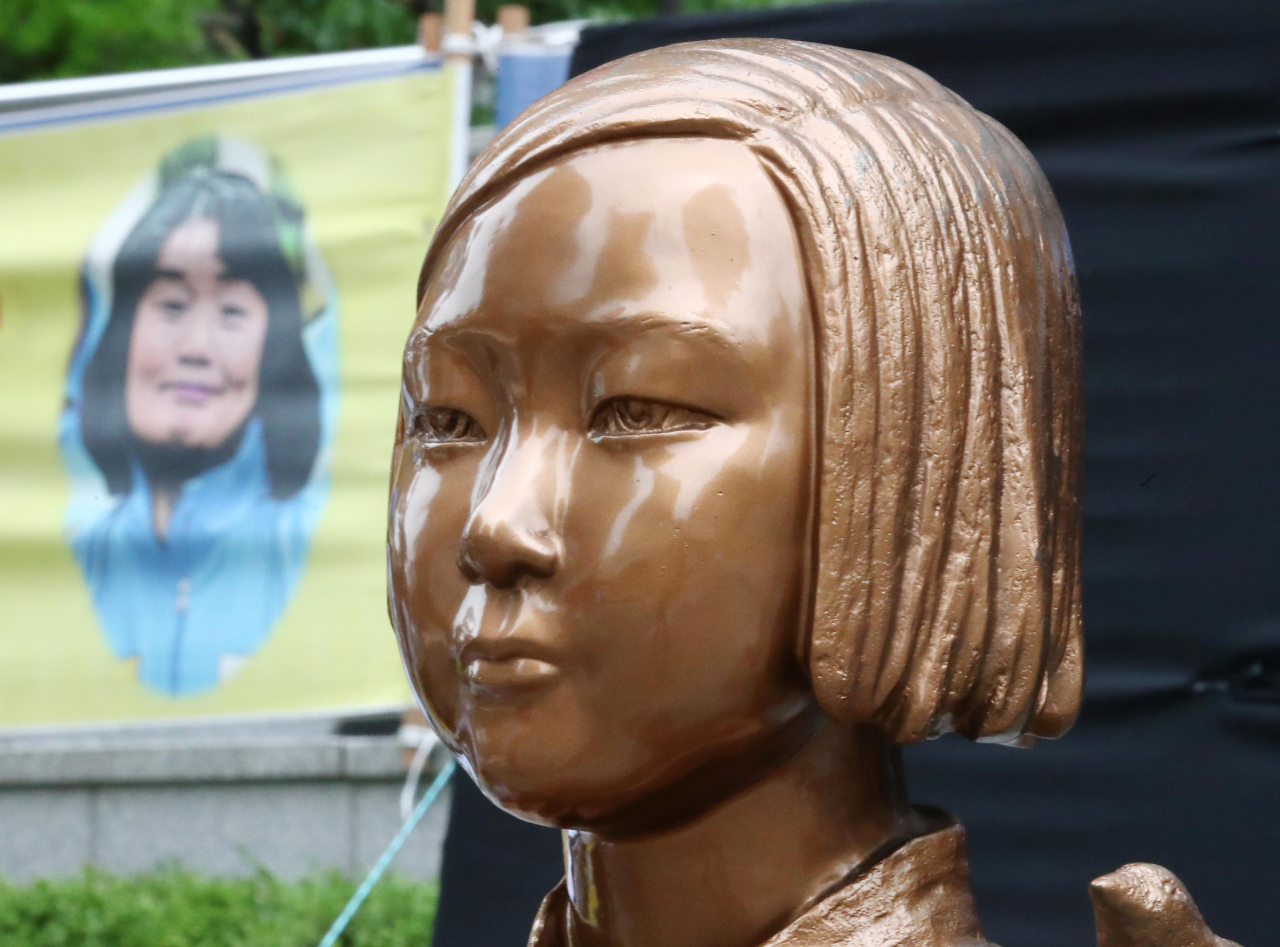 ‘일본군 위안부 피해자 기림의 날’인 지난 8월 14일 서울 종로구 옛 일본대사관 앞 소녀상 뒤로 정의기억연대 전 이사장 윤미향 의원의 사진이 담긴 현수막이 보이고 있다. [연합]