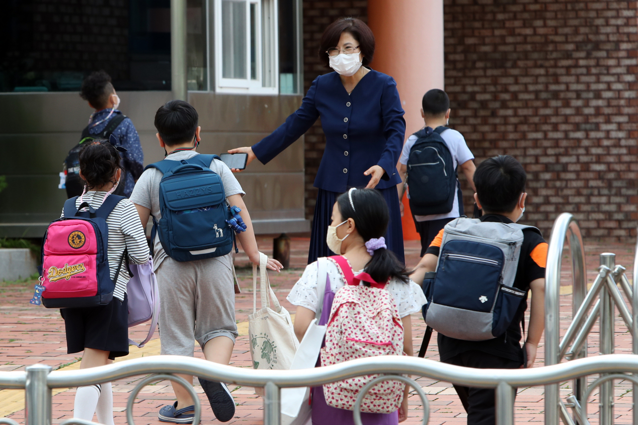 광주지역 각급 학교가 원격수업에서 부분 등교수업으로 전환한 14일 오전 광주 광산구 선암동 한 초등학교에서 교장 선생님이 학생을 맞이하고 있다. [연합]