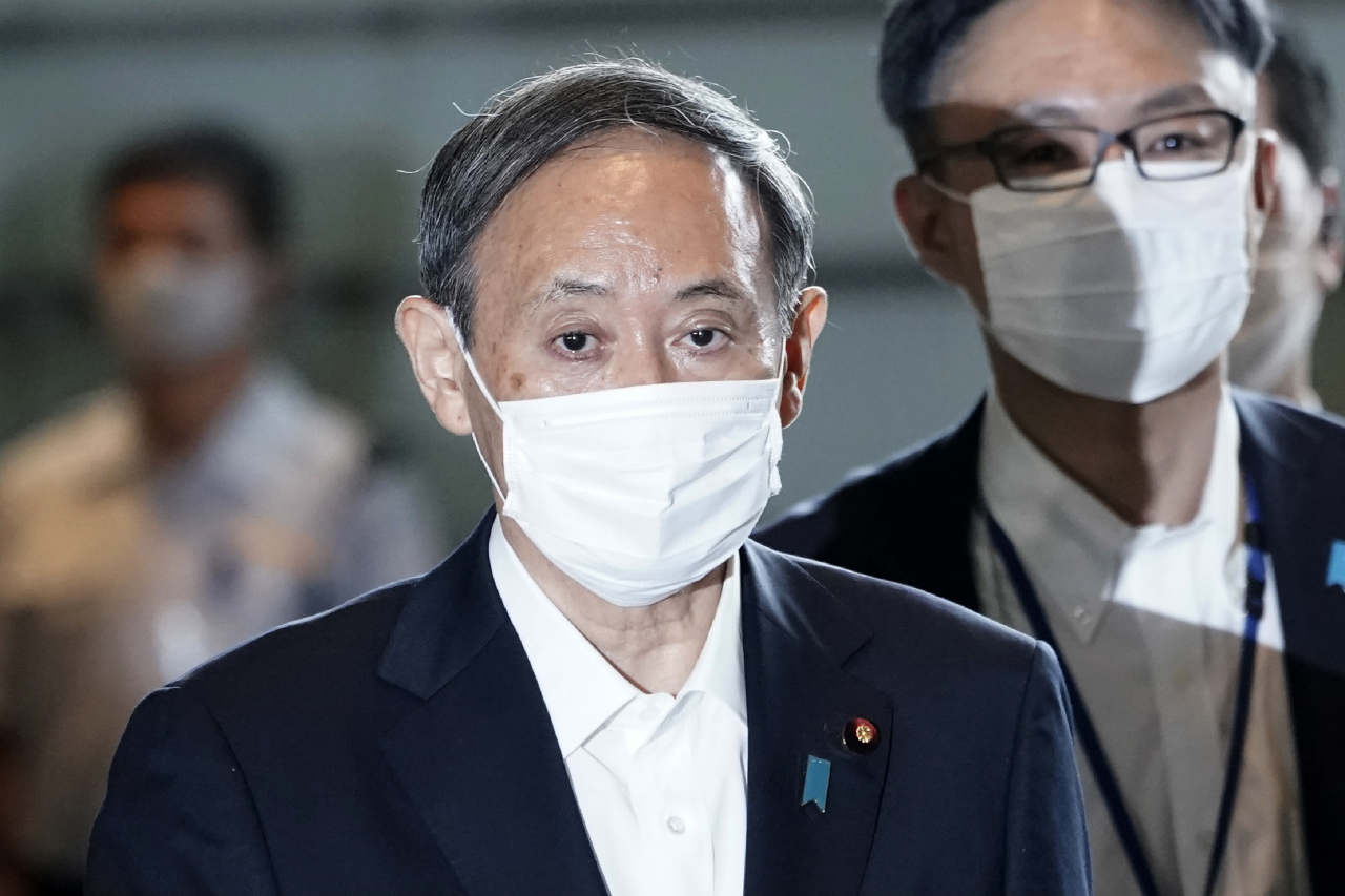 일본 집권 자민당의 스가 요시히데(菅義偉·가운데) 총재가 16일 도쿄에서 국무회의를 위해 총리실로 걸어가고 있다.[AP]