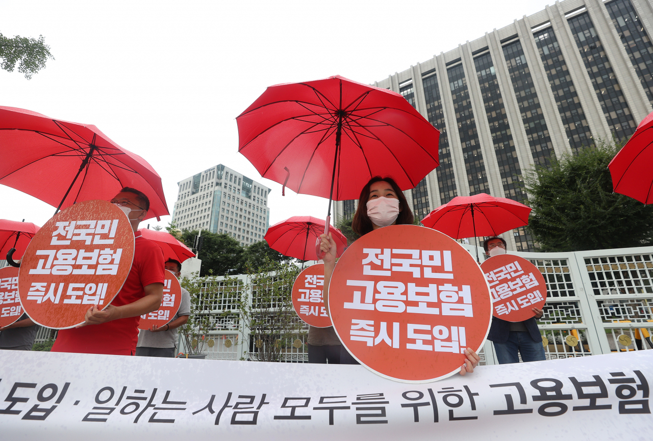 ㅈ난 8월 28일 오전 정부서울청사 앞에서 진보당 관계자들이 '제대로 된 전국민고용보험 운동본부 발족식'을 열고 빨간색 우산을 들고 퍼포먼스를 하고 있다. [연합]