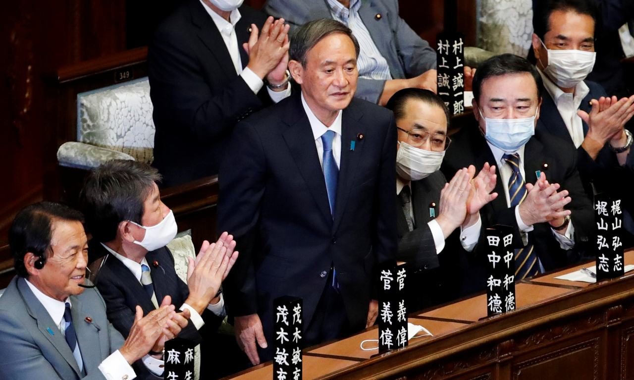 일본의 집권 자민당 스가 요시히데 총재가 16일 도쿄 중의원에서 새 총리로 선출된 직후 의원들의 박수를 받으며 자리에서 일어서 있다. [연합]