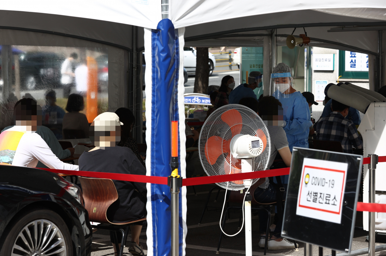 서울 강남구 소재 주상복합 건물과 부동산 관련 업체 등에서 잇따라 코로나19 확진자가 발생하고 있는 21일 오전 강남구보건소 선별진료소가 검사를 기다리는 시민들로 붐비고 있다. [연합]