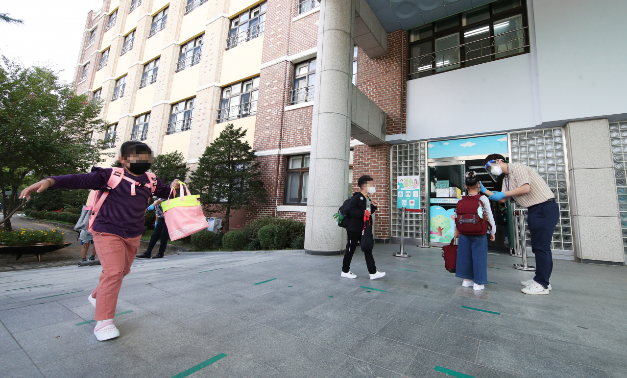 수도권 지역 유·초·중·고 학생들의 등교가 재개된 21일 오전 경기도 수원시 영통구 원일초등학교에서 학생들이 등교하며 체온을 재고 있다. [연합]