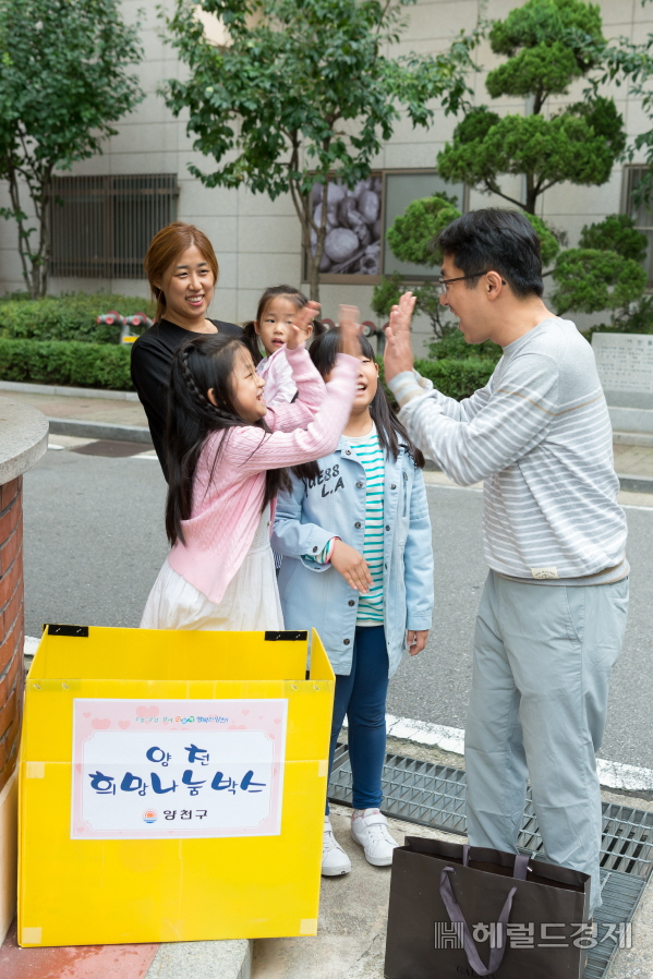 양천구 한 가족이 기부나눔 박스에 물품을 넣은뒤 기뻐하고 있다.[양천구 제공]