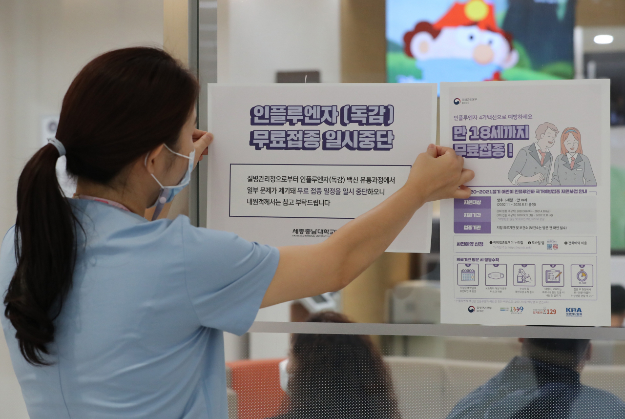 22일 오전 세종시에 있는 한 대형병원에서 인플루엔자(독감) 백신 무료접종 연기 안내문을 붙이고 있다. [연합]