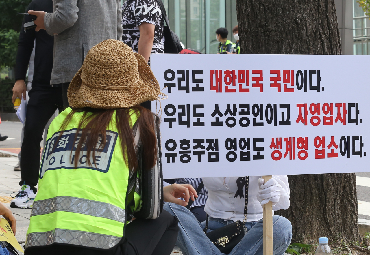 지난 14일 서울 여의도 국회 앞에서 열린 '유흥주점 2차 재난지원금 제외 규탄 기자회견'에서 경찰이 집회 참가자와 대화하고 있다. [연합]