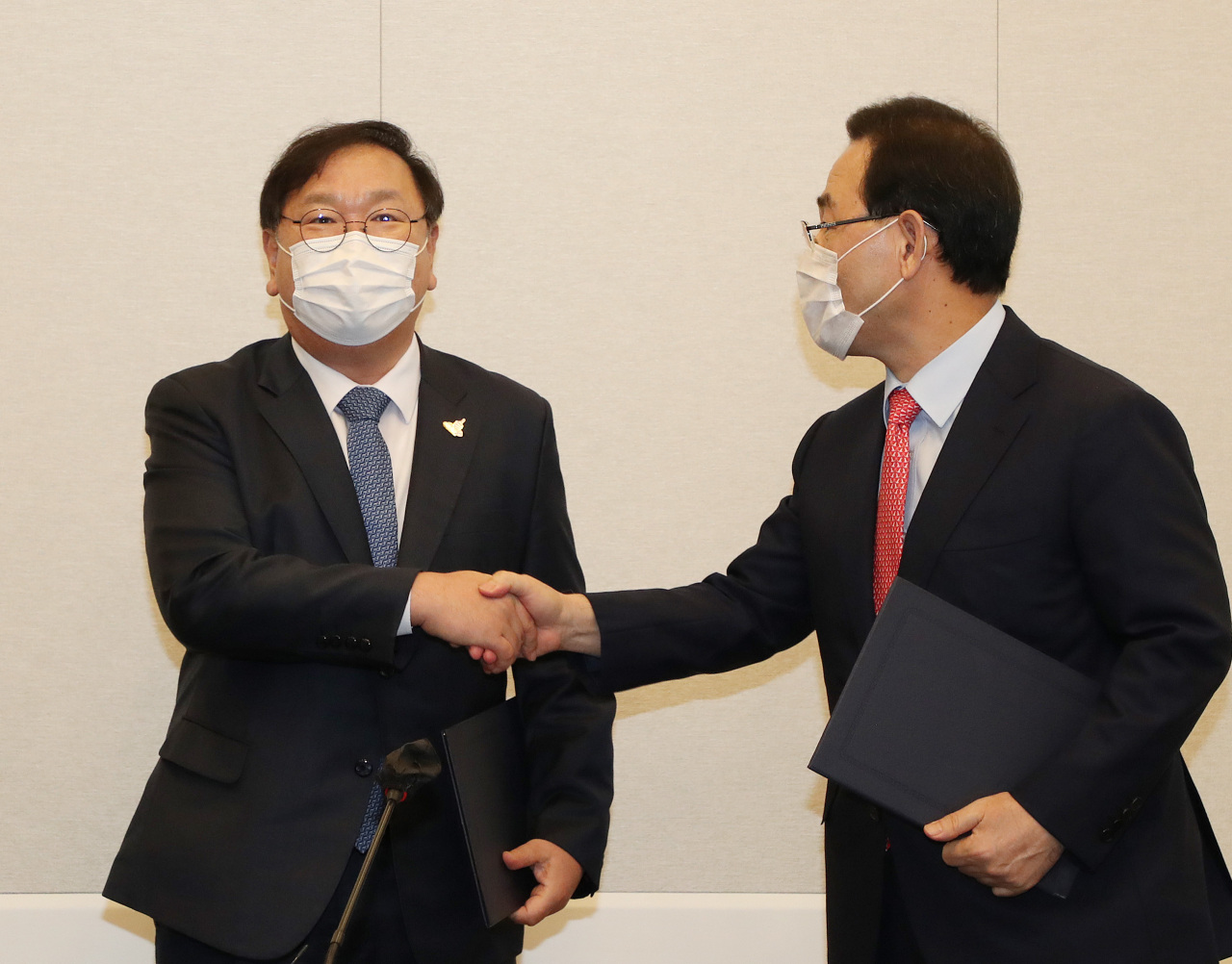 Democratic Party floor leader Rep. Kim Tae-nyeon and People Power Party floor leader Rep. Joo Ho-young shake hands after reaching an agreement on Tuesday. Yonhap