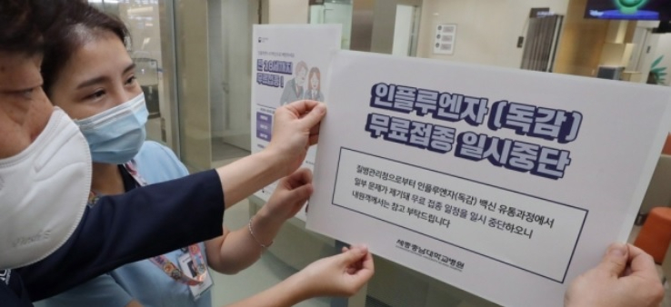 지난 22일 오전 세종에 있는 한 대형 병원에서 직원들이 인플루엔자(독감) 백신 무료 접종 연기 안내문을 붙이고 있다. [연합]