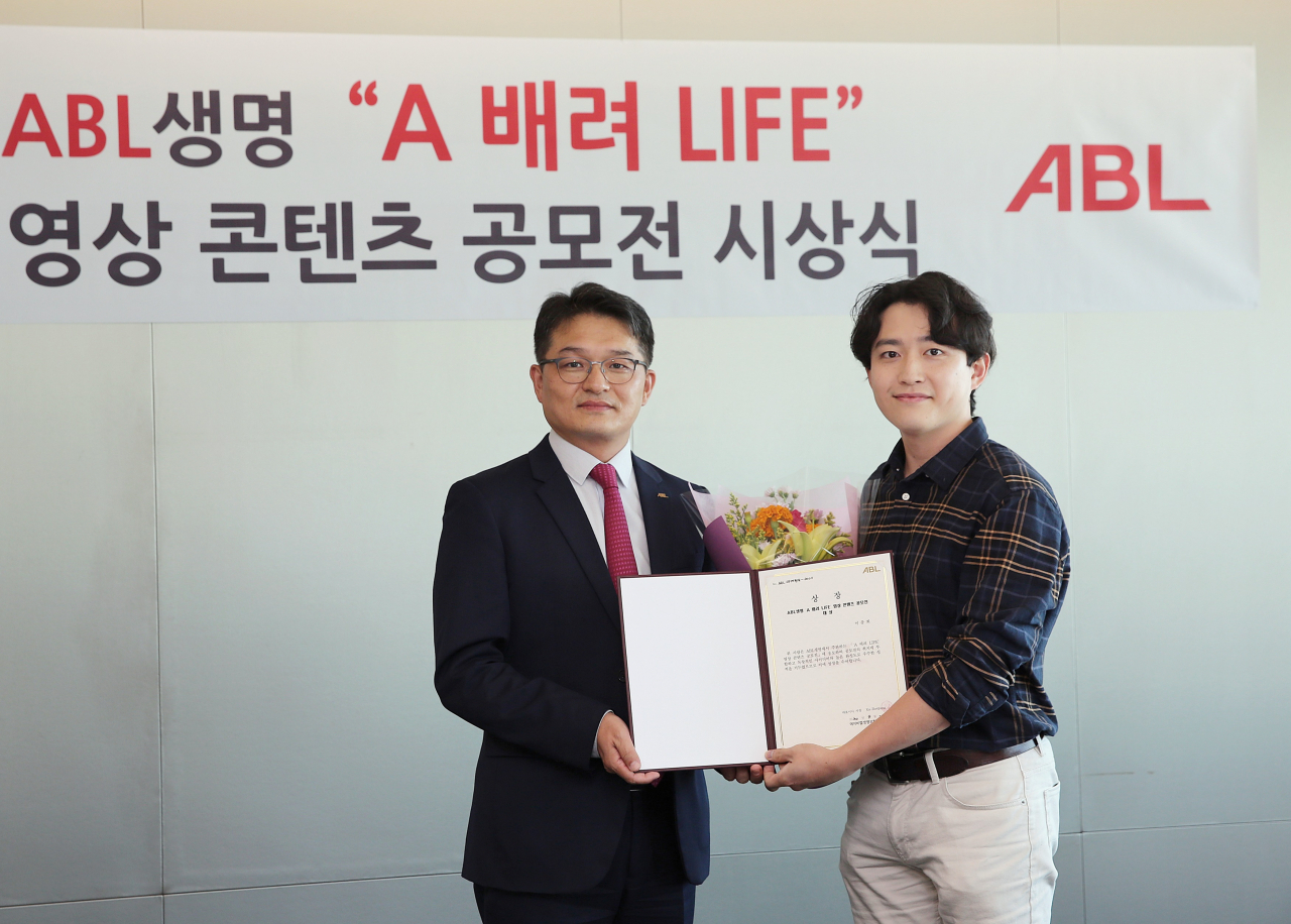 ABL생명이 22일 서울 여의도 본사에서 개최한 ‘A 배려 LIFE’ 영상 콘텐츠 공모전 시상식에서 은재경 ABL생명 상품&마케팅실장(왼쪽)과 대상 수상자인 연세대학교 언론영상학부 이충희 군이 기념사진을 촬영하고 있다. 출처=ABL생명.