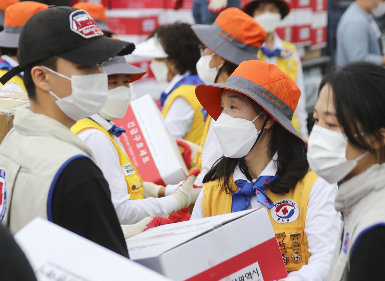 부산적십자 자원봉사원과 RCY 단원 등이 23일 부산시민공원 야외주차장에서 부산시 공공기관의 후원으로 제작된 코로나19 긴급구호품을 화물차에 싣고 있다. 긴급구호품은 코로나19 자가격리 세대와 재난 취약계층 총 5000세대에게 전달할 예정이다. [연합]