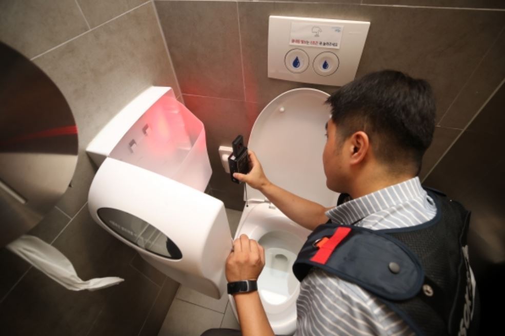 An official inspects a bathroom stall for hidden cameras. (Yonhap)