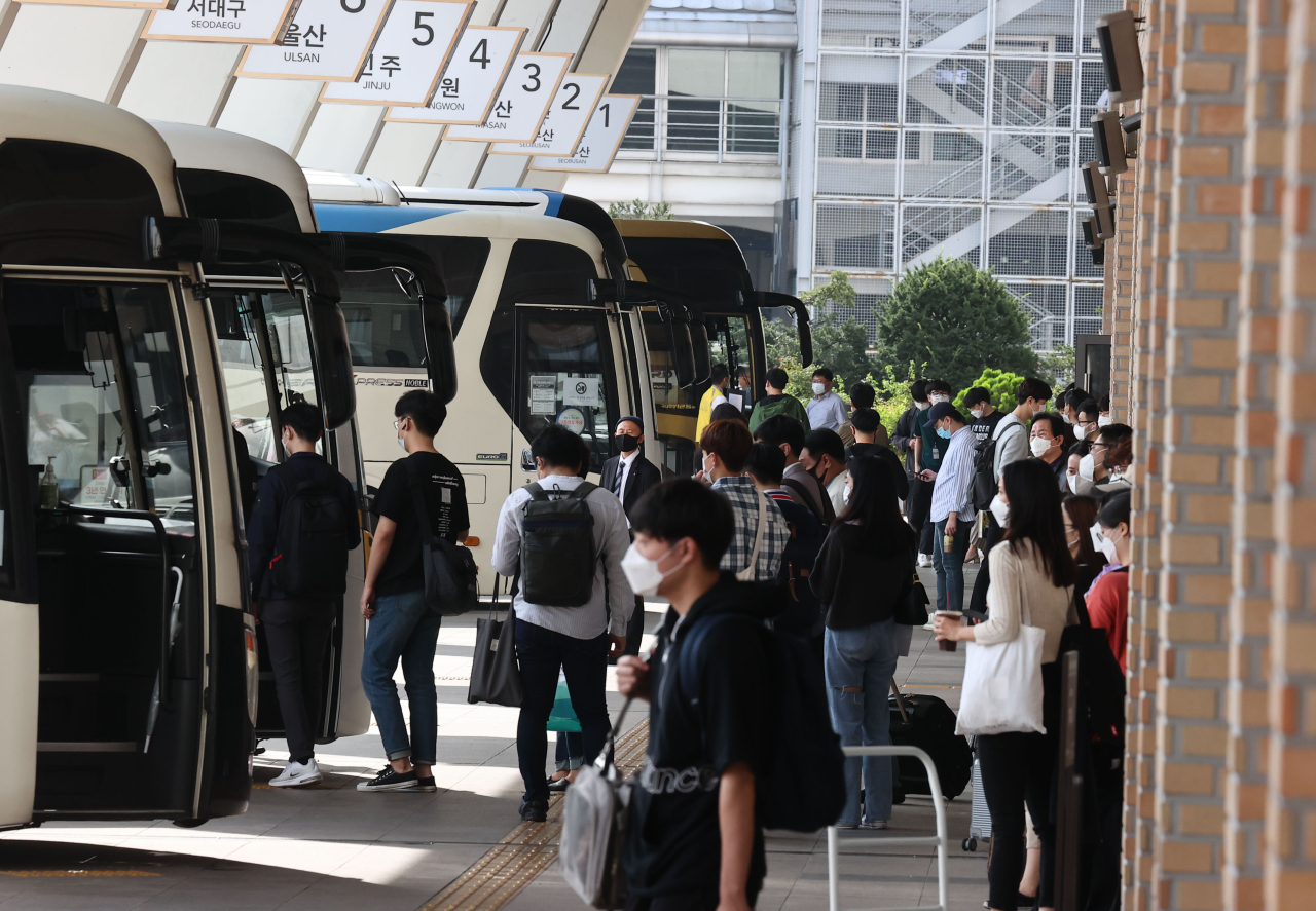 Travellers board buses at a terminal in Seoul on Tuesday. Yonhap
