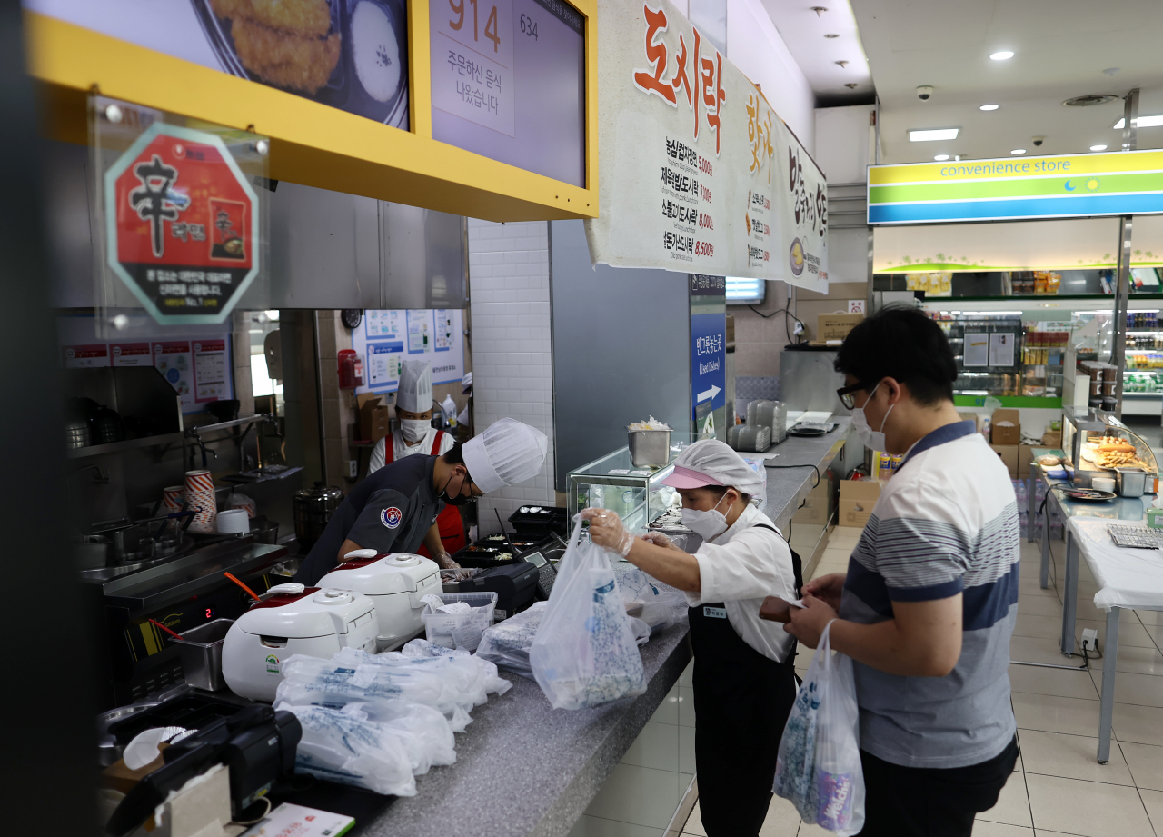 코로나19 확산방지를 위해 29부터 다음 달 4일까지 총 6일간 고속도로 휴게소 실내매장에서는 좌석 운영이 금지된다. 대신 음식물을 포장해 갖고 가는 테이크아웃은 가능하다. 29일 오후 서초구 서울만남의광장(부산방향) 식당에서 한 시민이 주문한 도시락을 받고 있다. [연합]