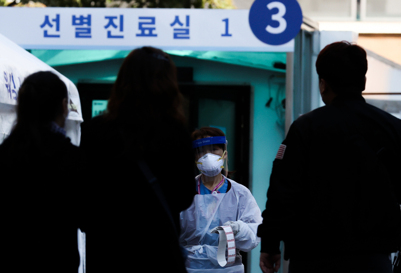 6일 오전 서울 중구 국립중앙의료원 신종 코로나바이러스 감염증(코로나19) 선별진료소에서 관계자가 검체 채취 신청자의 이름이 적힌 스티커를 들고 대기자들을 향해 가고 있다. [연합]