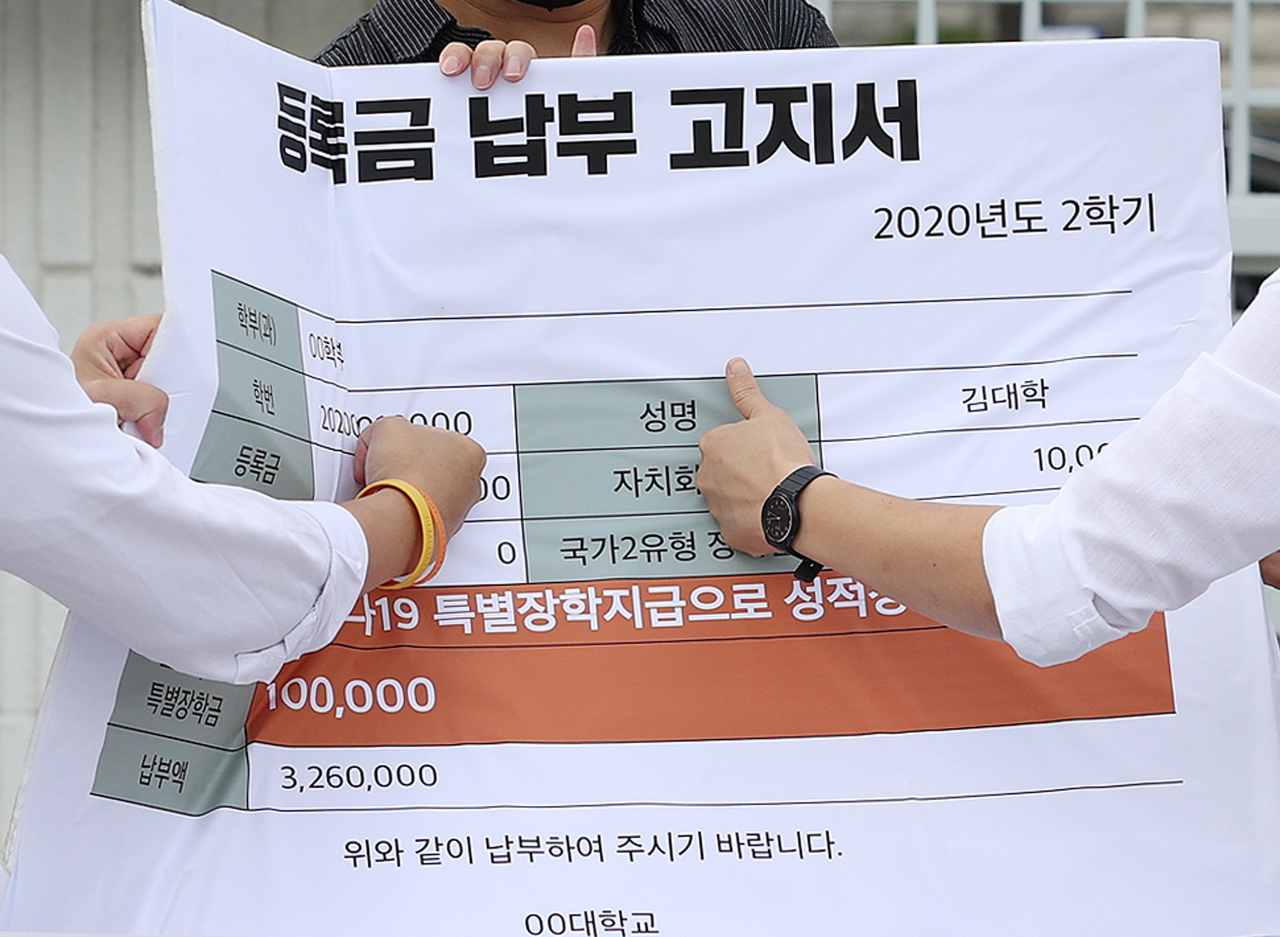 청년진보당 관계자들이 지난 달 10일 오전 정부서울청사 앞에서 열린 코로나시대 대학생 권리찾기 운동 선포 기자회견에서 등록금 100만원 상한제 추진 및 등록금 반환에 대한 교육부의 관리감독과 기준 마련을 촉구하며 등록금 납부 고지서를 주먹으로 치는 퍼포먼스를 하고 있는 모습. [연합]