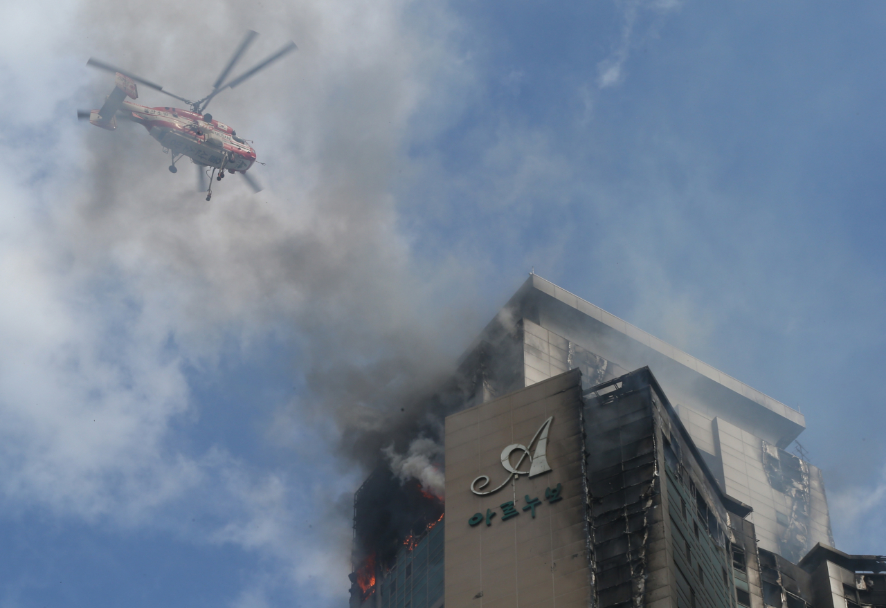 8일 오후 울산시 남구 한 주상복합아파트에서 난 화재가 9일 오전까지 꺼지지 않아 헬기가 동원돼 진화 작업을 하고 있다. [연합]